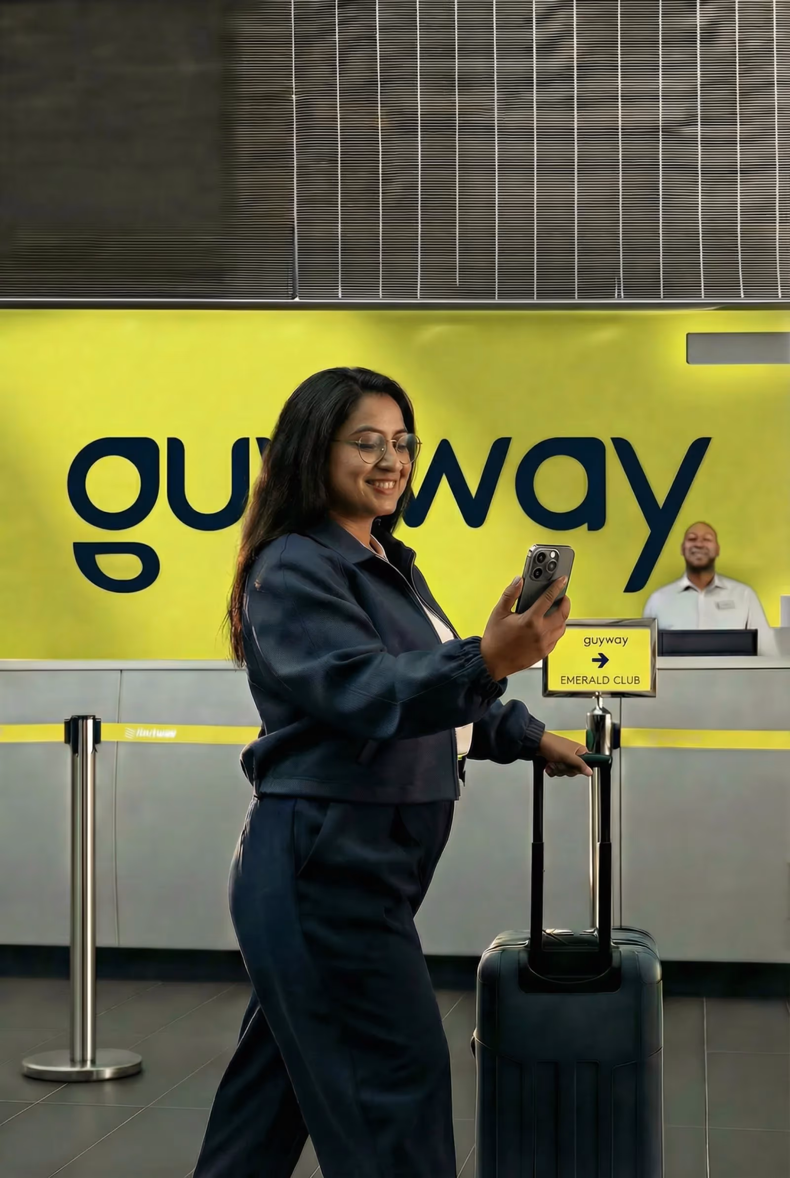 A business traveller with a rolling suitcase walks past the branded GuyWay check-in counter at Cheddi Jagan International Airport — on-demand corporate airport transfers for companies in Guyana