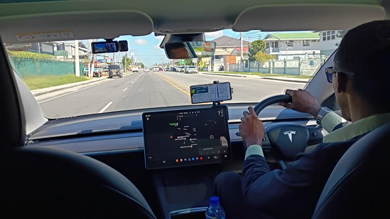 Un conductor de GuyWay al volante en una calle de Georgetown, con la navegación en la pantalla del tablero