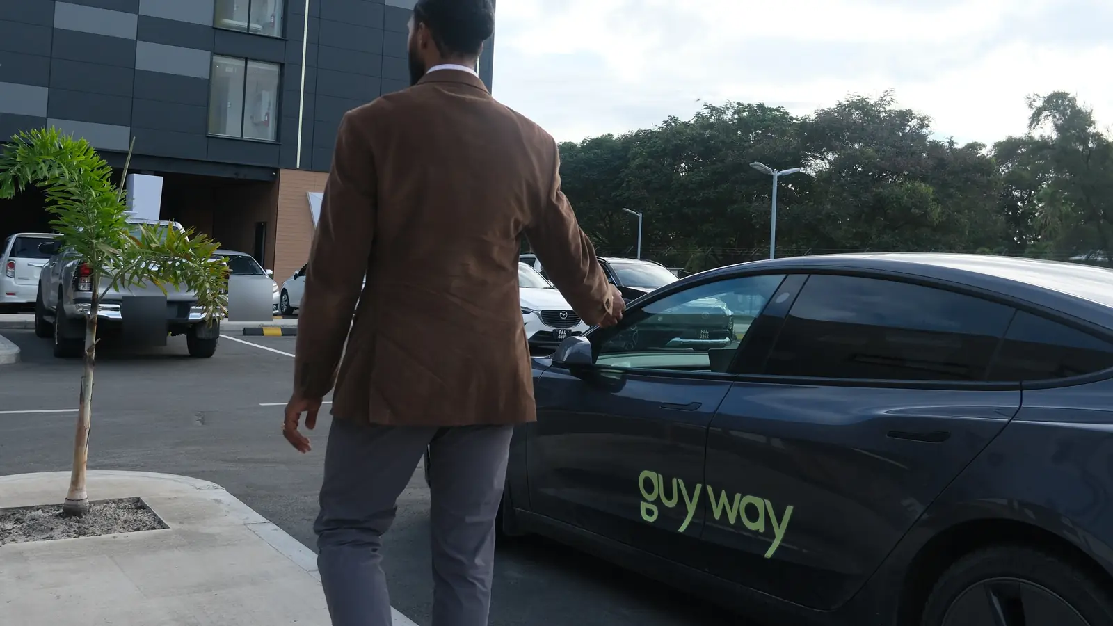 Un pasajero camina hacia un Tesla de GuyWay afuera del AC Hotel by Marriott