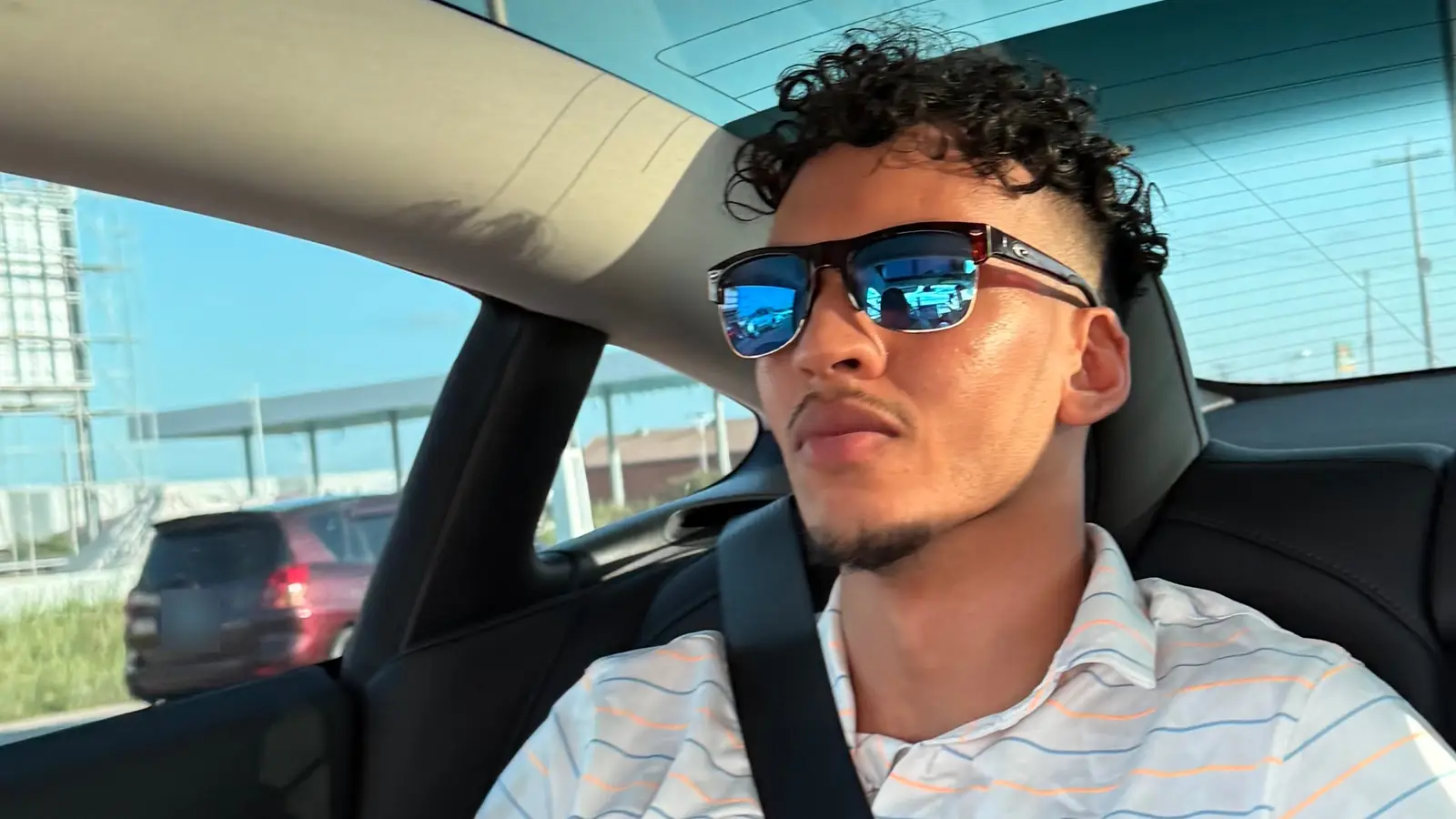 A passenger in sunglasses in the back seat of a GuyWay Tesla