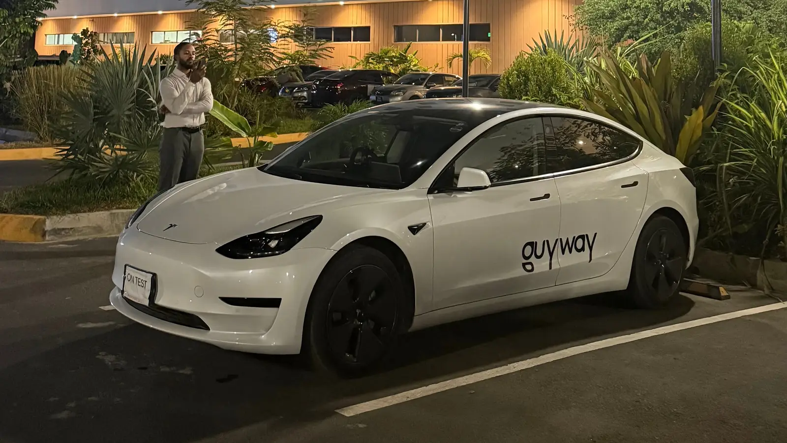 White GuyWay Tesla Model 3 outside a hotel at night