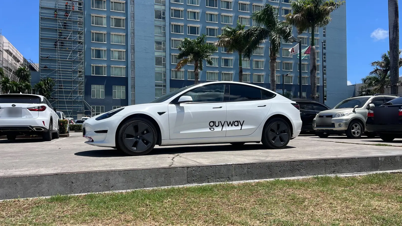 Tesla Model 3 blanco de GuyWay en el estacionamiento del hotel Marriott, Georgetown