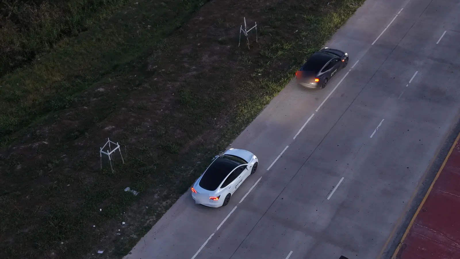 White and dark grey GuyWay Teslas driving on a concrete highway, seen from above