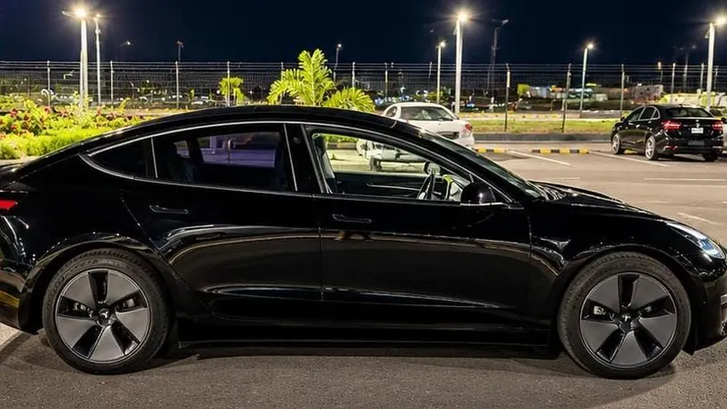 Side view of a black GuyWay Executive Tesla Model 3 with no GuyWay sign, in a car park at night