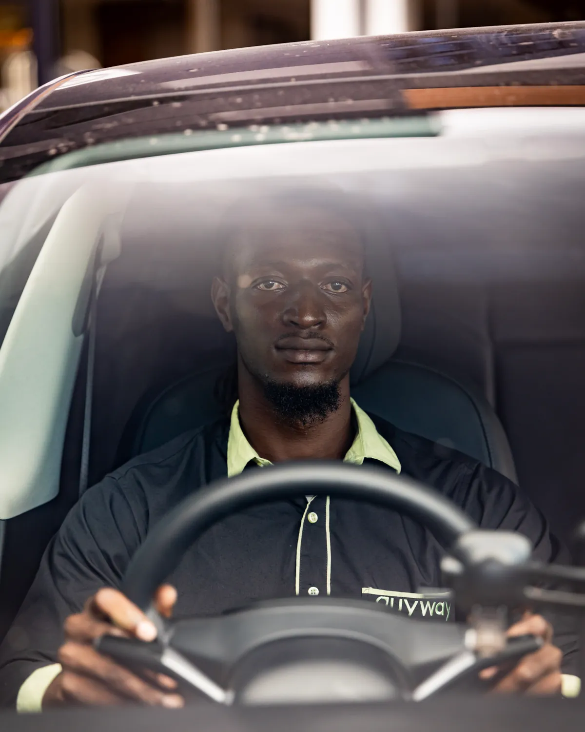 A GuyWay driver in uniform at the wheel, seen through the windscreen