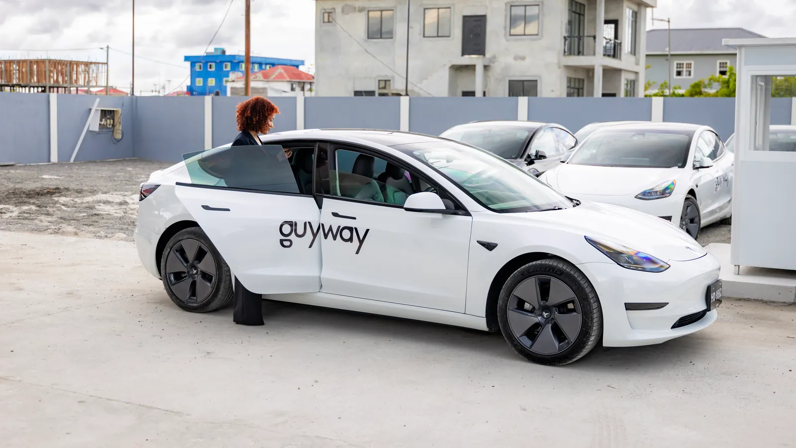 A rider gets into a white GuyWay Tesla Model 3 at the GuyWay hub in Providence
