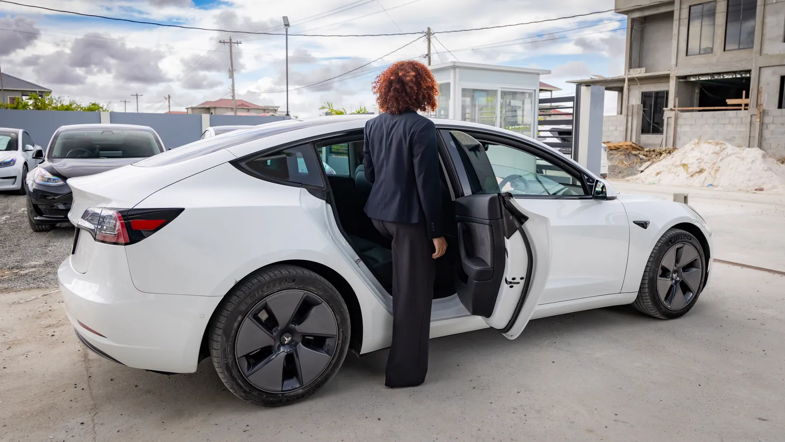 A rider opens the rear door of a white GuyWay Tesla