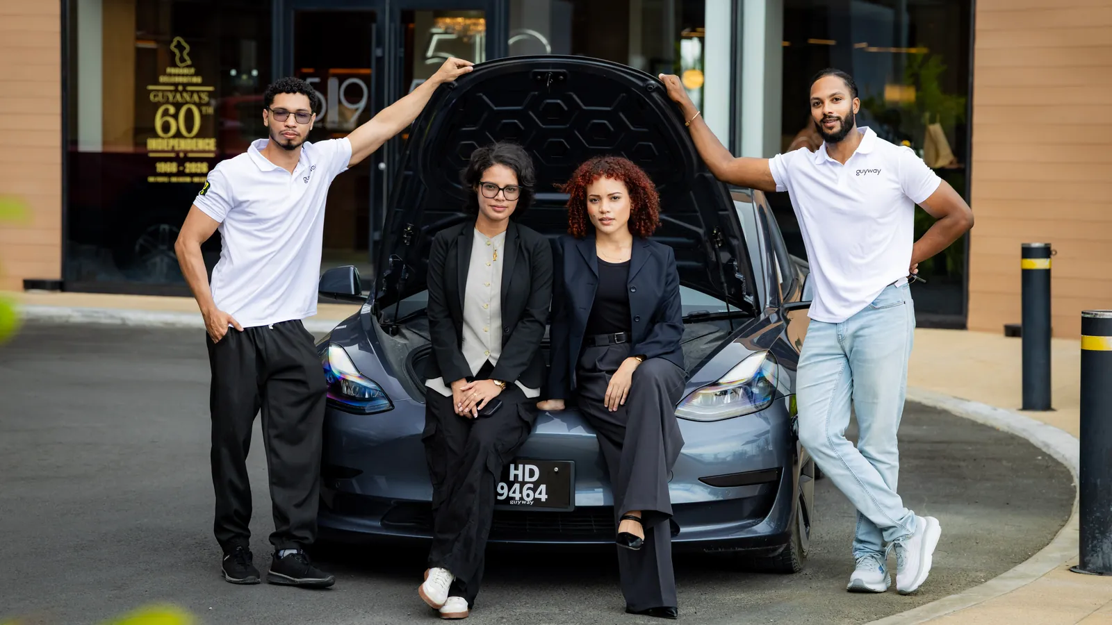 Four GuyWay team members around a grey GuyWay Tesla outside a hotel in Georgetown