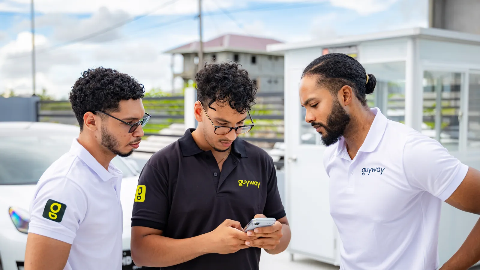 Three GuyWay team members checking a booking on a phone at the GuyWay hub