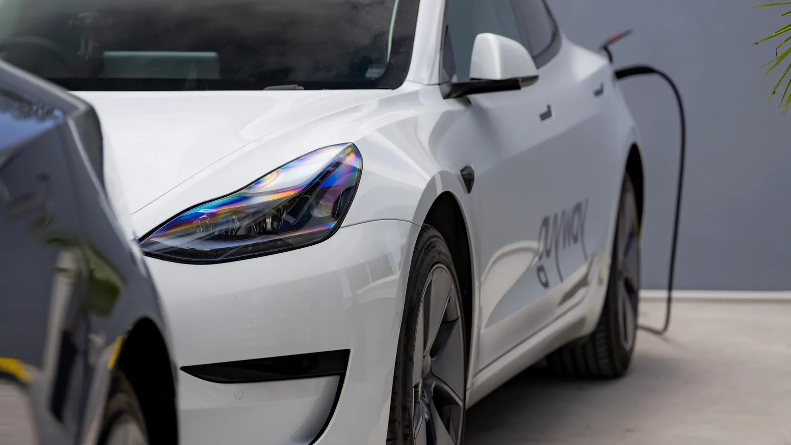 A white GuyWay Tesla Model 3 plugged in to charge at the GuyWay hub in Providence