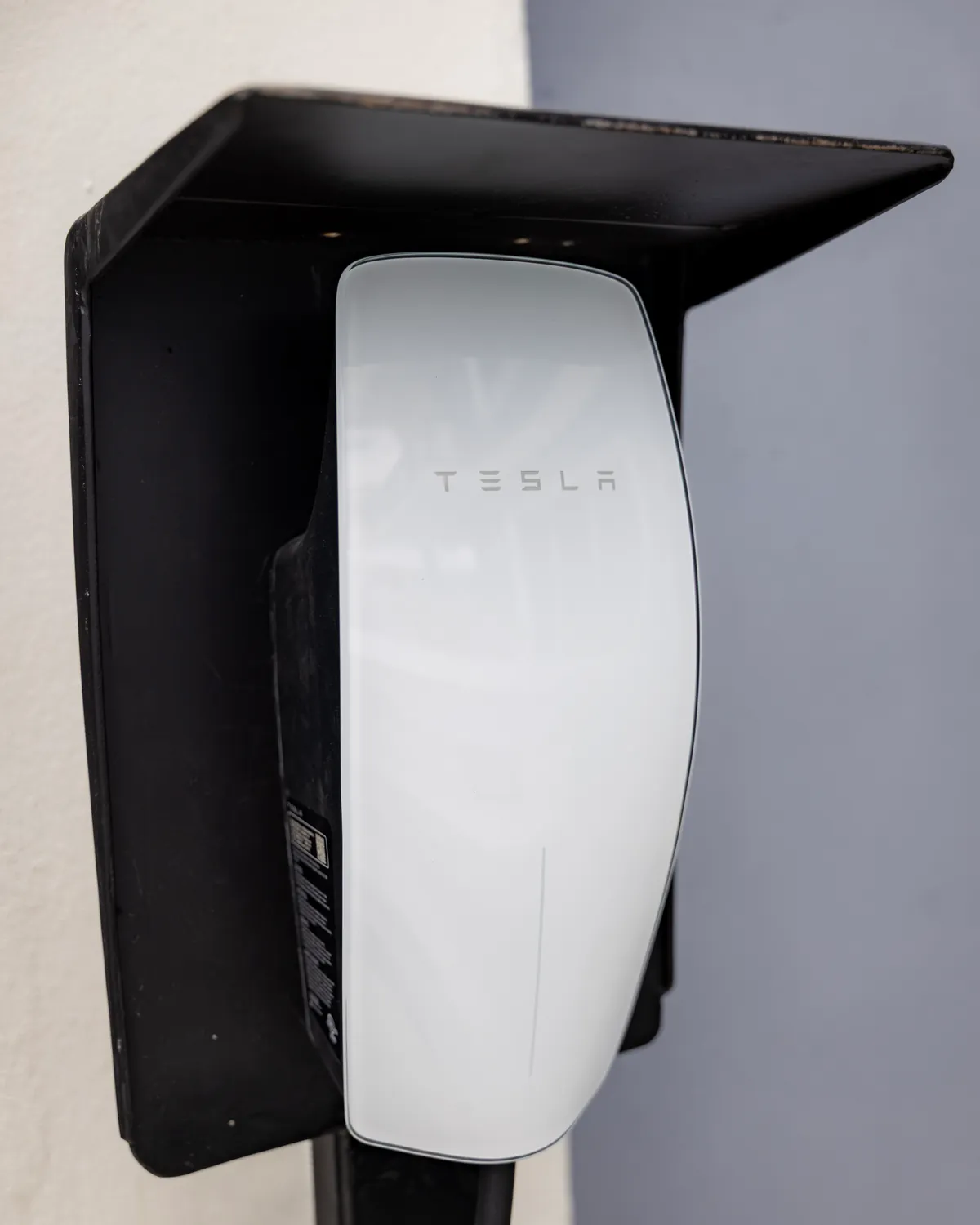 A Tesla wall charger under its rain hood at the GuyWay hub in Providence